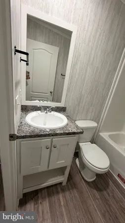 a bathroom with a granite countertop toilet sink and mirror