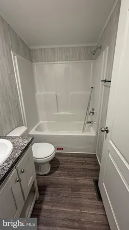 a bathroom with a granite countertop bathtub shower sink vanity and toilet