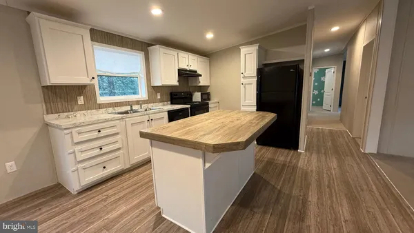 a kitchen with a refrigerator a stove top oven a sink dishwasher and wooden floor