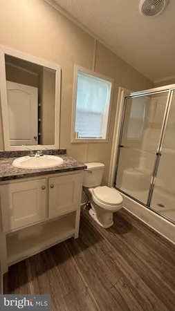 a bathroom with a granite countertop sink toilet a mirror and shower