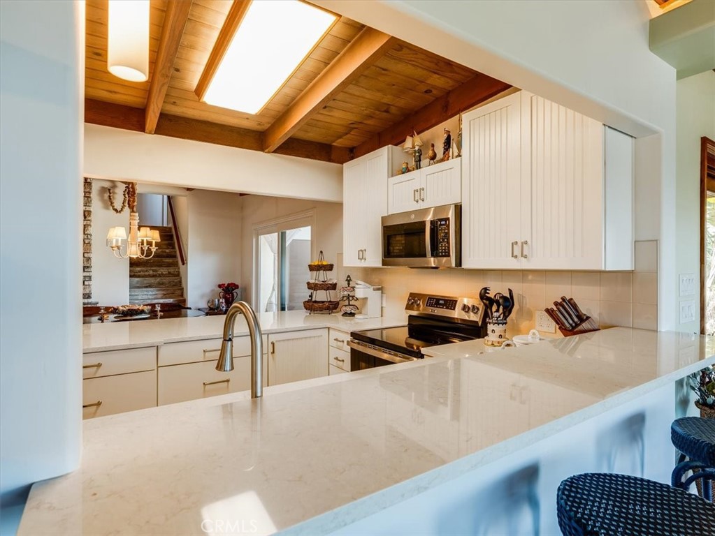 430 Olive Street Morro Bay, CA 93442 - Photo 17 of 68 a kitchen with stainless steel appliances kitchen island granite countertop a sink and white cabinets
