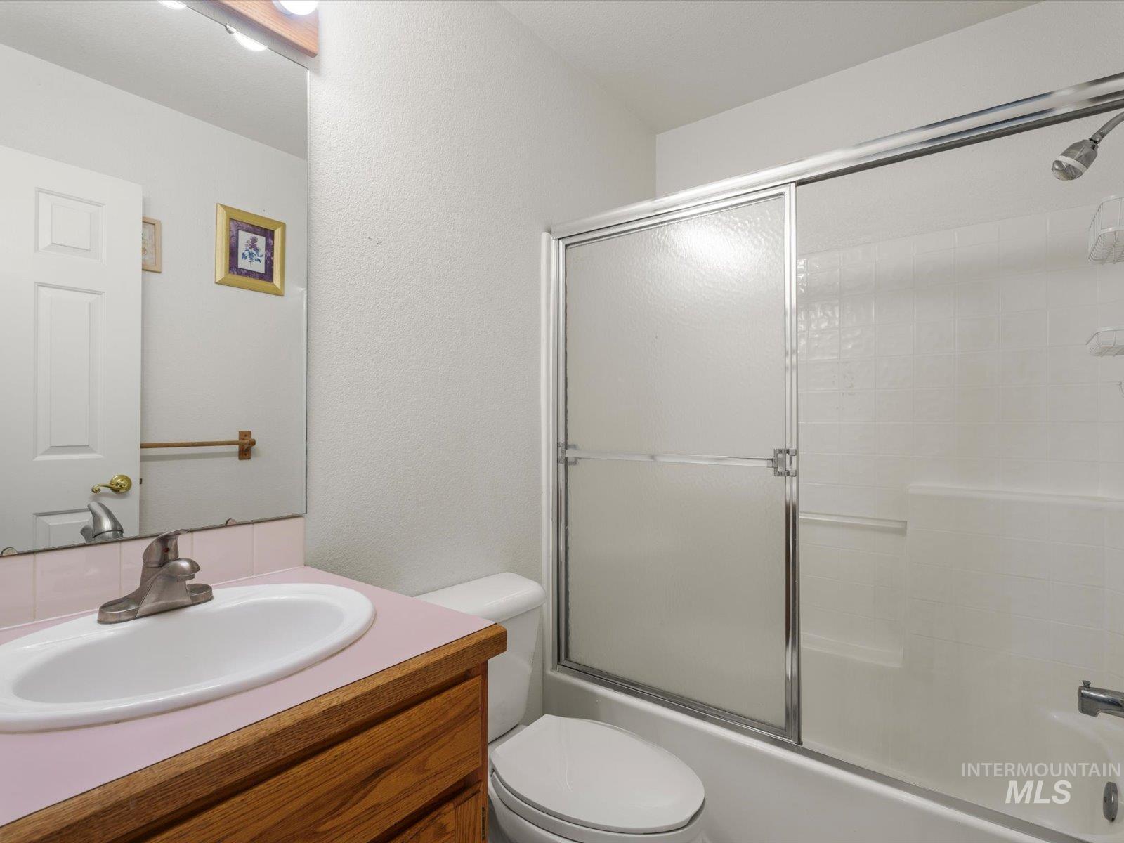 3540 Wills Road Emmett, ID 83617 - Photo 22 of 36 Bathroom featuring a wood-finish vanity with a pink laminate countertop, integrated sink, and brushed nickel faucet