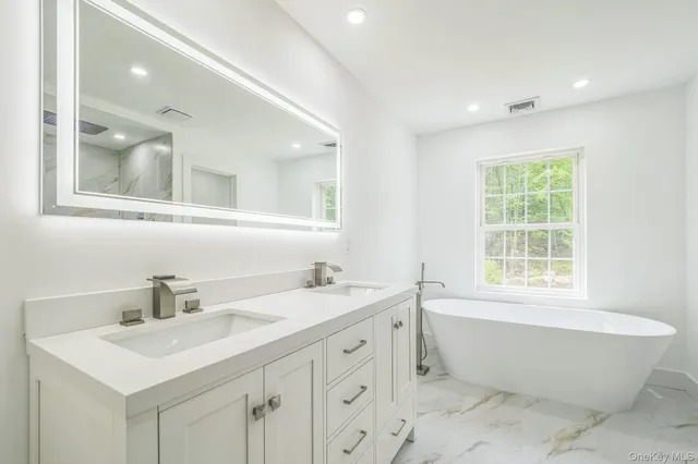 a bathroom with a sink mirror vanity bathtub and next to a window