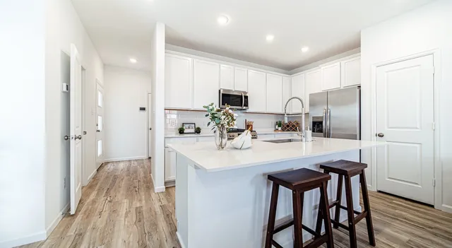 a kitchen with kitchen island a stove a refrigerator and a sink with wooden floor