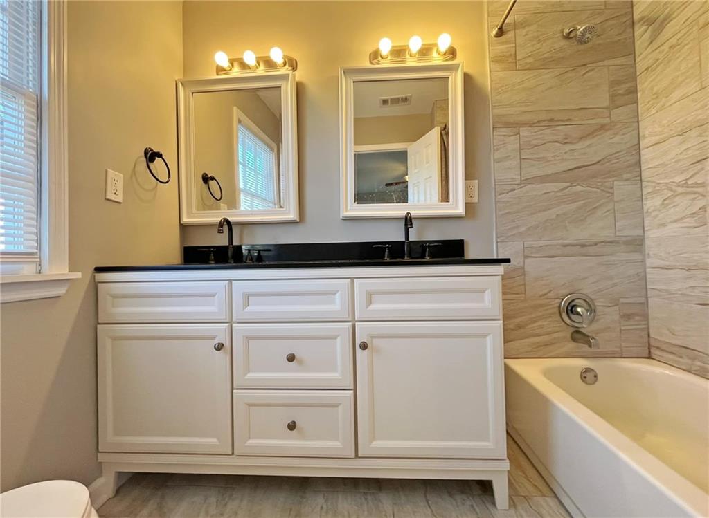 6520 Roswell Road, Unit 3 Atlanta, GA 30328 - Photo 27 of 47 a bathroom with a granite countertop sink a toilet mirror and bathtub