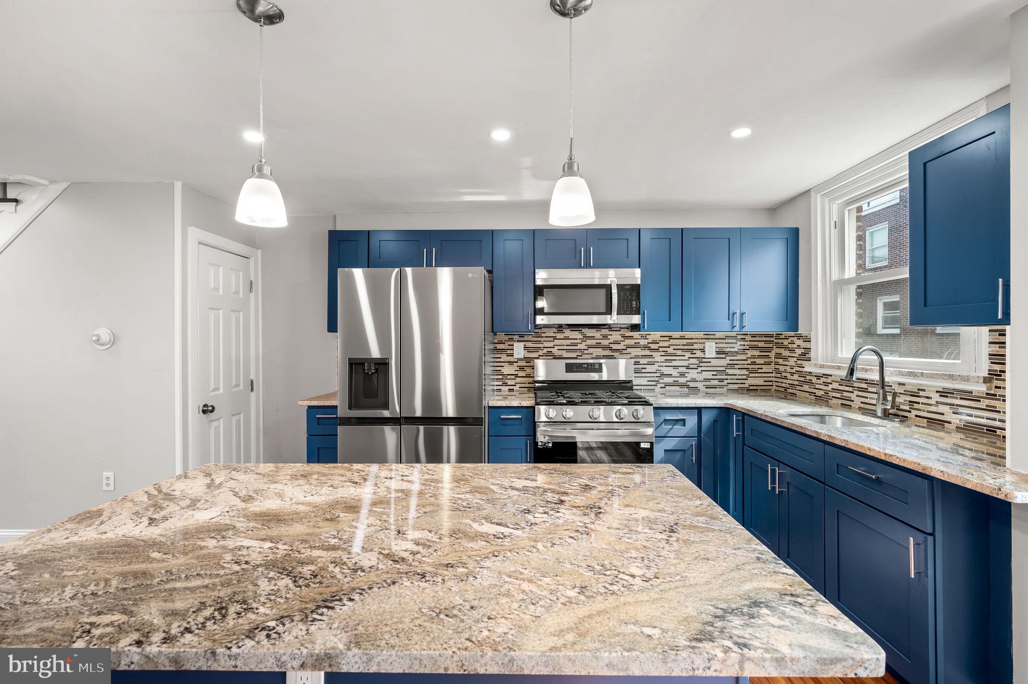 a kitchen with stainless steel appliances kitchen island granite countertop a refrigerator sink and cabinets