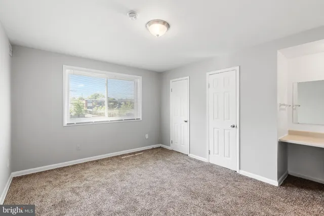 a view of an empty room with closet and a window
