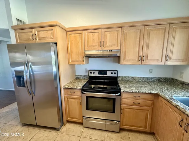 a kitchen with granite countertop a stove top oven cabinets and stainless steel appliances