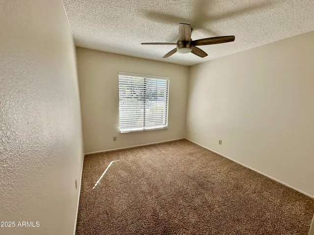 an empty room with windows and fan