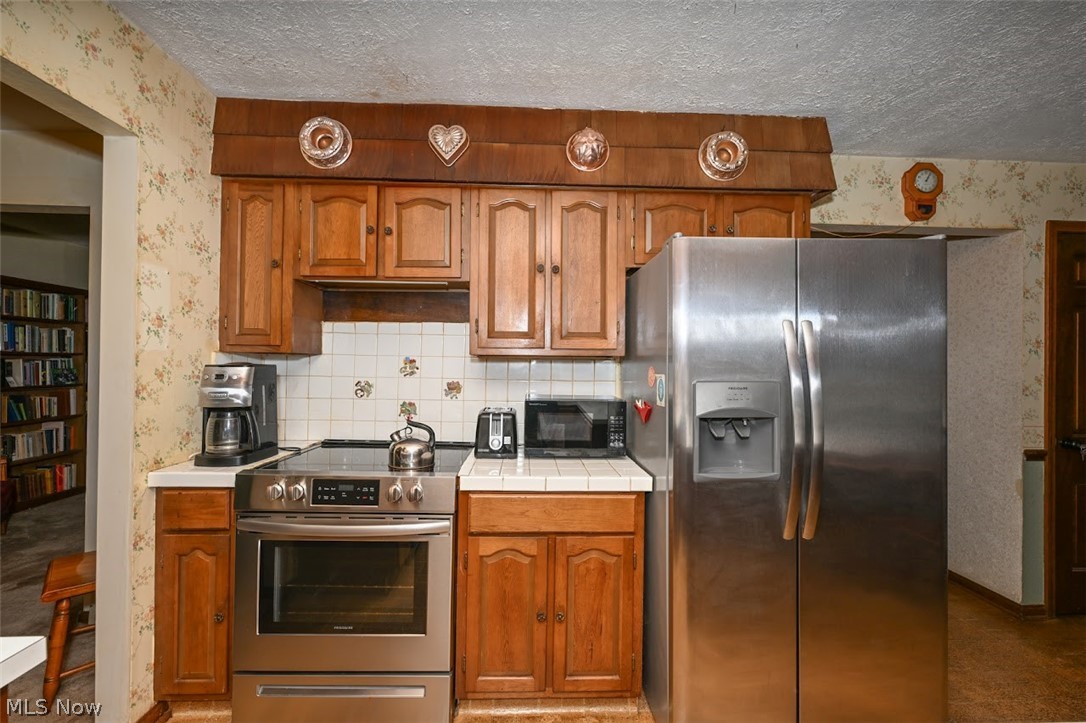 758 Inverness Road Akron, OH 44313 - Photo 15 of 46 Kitchen featuring a textured ceiling, tasteful backsplash, and stainless steel appliances