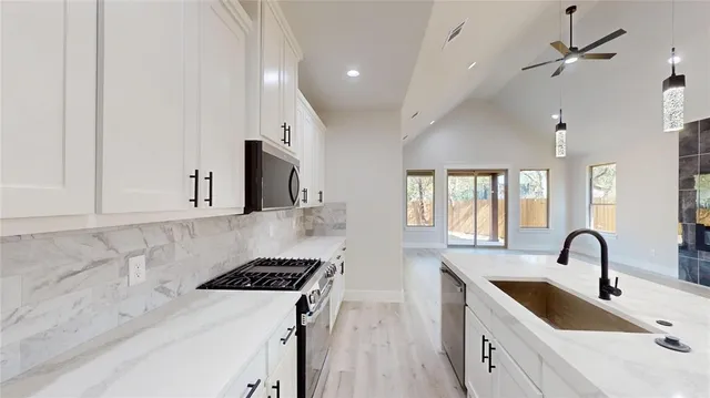 a kitchen with granite countertop a stove a sink a center island and windows