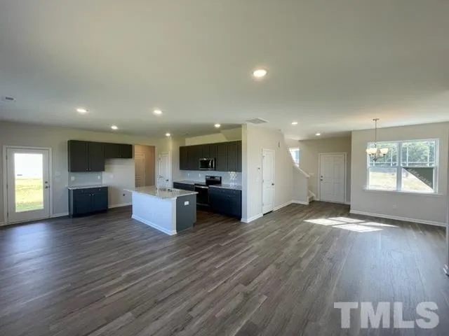 an empty room with kitchen view and a flat screen tv