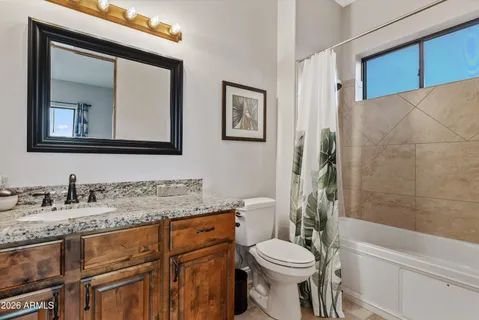 a bathroom with a granite countertop toilet sink and mirror