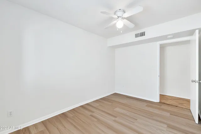 an empty room with wooden floor and fan