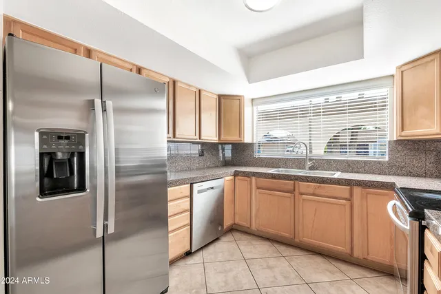 a kitchen with stainless steel appliances granite countertop a sink and a refrigerator