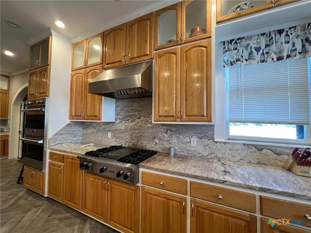 a kitchen with stainless steel appliances granite countertop a sink stove and cabinets