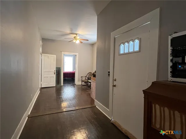 a view of a hallway with wooden floor and a living room