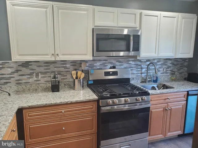 a kitchen with granite countertop white cabinets stainless steel appliances and a sink