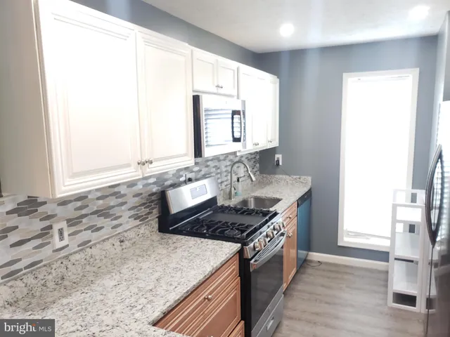 a kitchen with stainless steel appliances granite countertop a sink and a stove