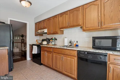 a kitchen with stainless steel appliances granite countertop a stove a sink dishwasher and a refrigerator with wooden cabinets