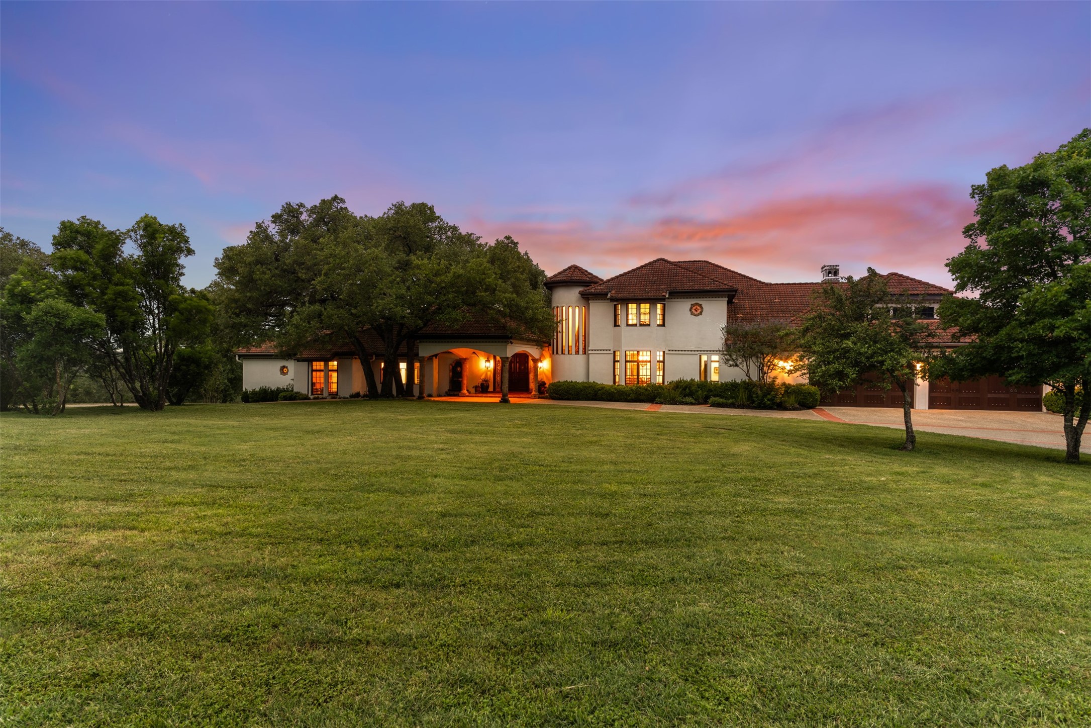34000 Smithson Valley Road Bulverde, TX 78163 - Photo 47 of 50 As evening falls, the estate comes alive with warm architectural lighting that highlights its timeless Mediterranean design. The grand façade and mature landscaping create a truly unforgettable first impression.