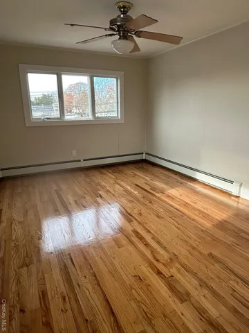 an empty room with wooden floor chandelier and windows