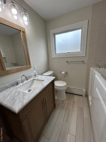 a bathroom with a granite countertop sink a toilet and a mirror