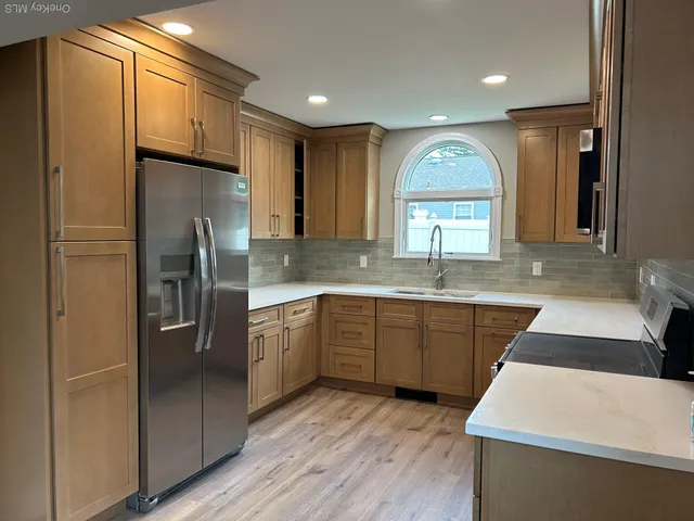 a kitchen with stainless steel appliances granite countertop a refrigerator a sink a stove and island with wooden floor