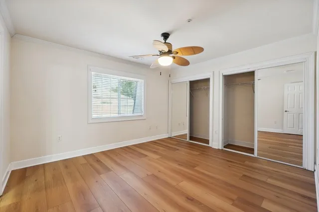 a view of empty room with wooden floor and fan