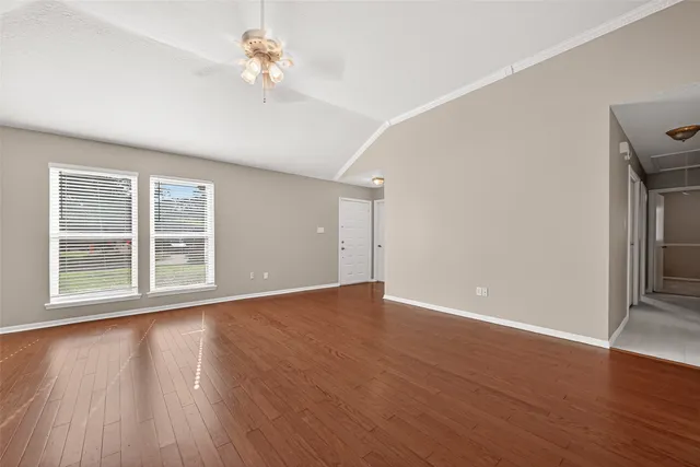 a view of an empty room with wooden floor and a window