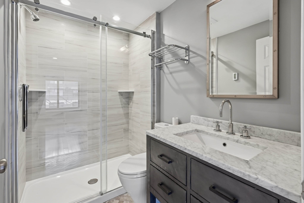 85 Brainerd Road, Unit TH7 Boston, MA 02134 - Photo 17 of 41 a bathroom with a sink granite countertop toilet a mirror and shower