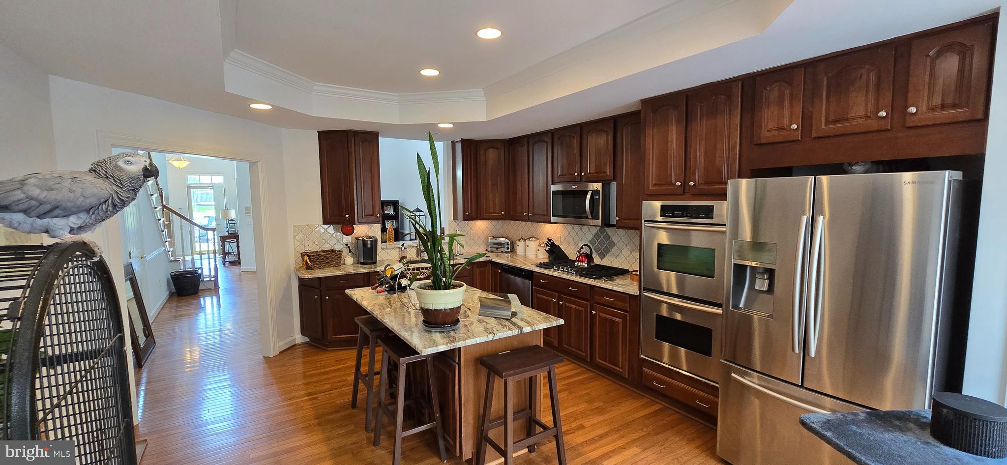 7357 Cluster House Way Gainesville, VA 20155 - Photo 13 of 28 a kitchen with granite countertop a refrigerator a stove and a wooden cabinets