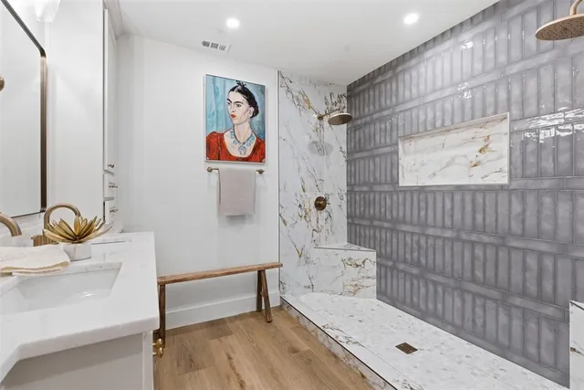 a bathroom with a tub a sink and wooden floor