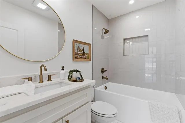 a bathroom with a granite countertop sink a toilet and bathtub