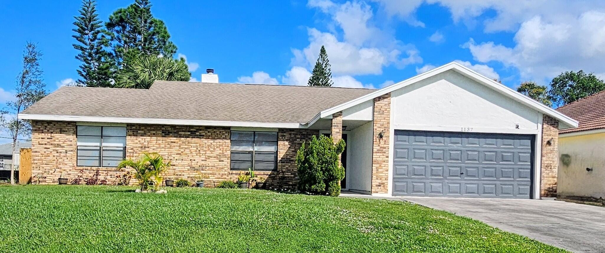 1137 Southwest Estaugh Avenue Port St. Lucie, FL 34953 - Photo 1 of 11 front view of a house with a yard