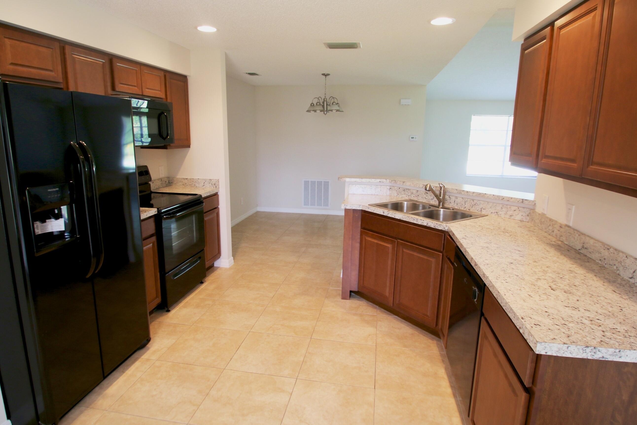 1137 Southwest Estaugh Avenue Port St. Lucie, FL 34953 - Photo 3 of 11 a kitchen with stainless steel appliances granite countertop a stove a refrigerator and a sink