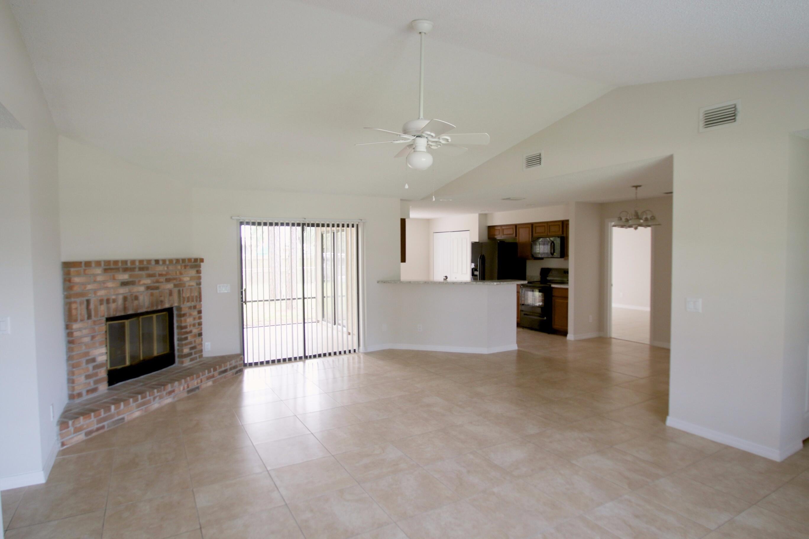 1137 Southwest Estaugh Avenue Port St. Lucie, FL 34953 - Photo 4 of 11 an empty room with kitchen and a fireplace