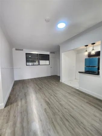 a view of empty room with kitchen and window