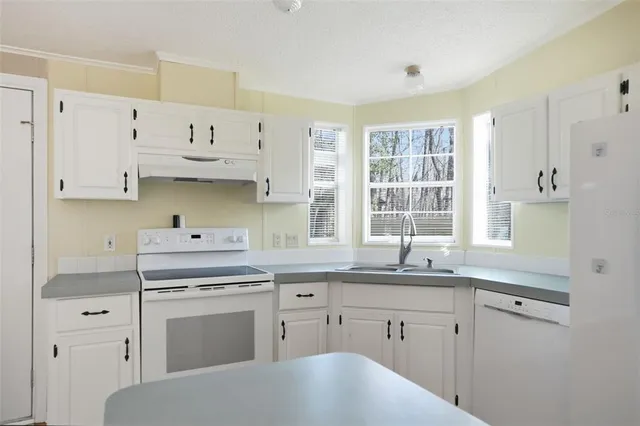 a kitchen with cabinets appliances a sink and a window