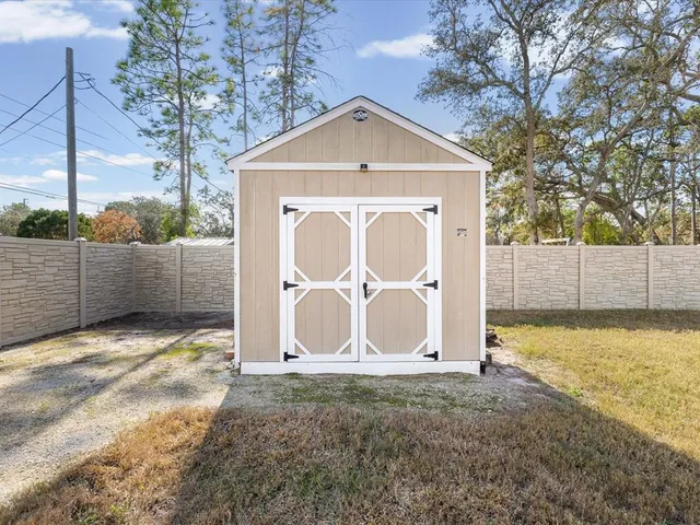 a view of a white house with a yard plants and large tree