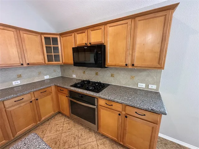 a open kitchen with kitchen island granite countertop a stove a sink a counter space and cabinets
