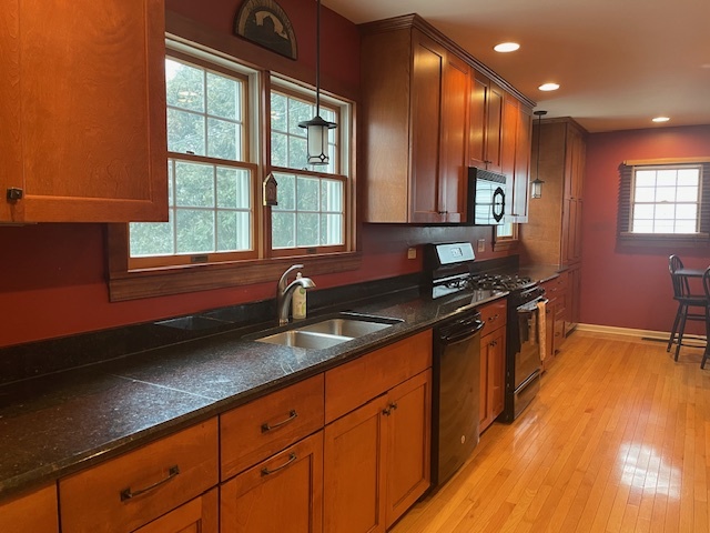 1505 West Acres Road Joliet, IL 60435 - Photo 12 of 42 a kitchen with granite countertop a sink a stove cabinets and wooden floor
