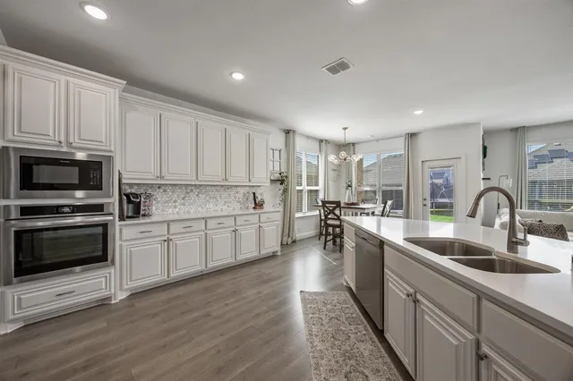 a kitchen with counter top space a sink wooden floor and stainless steel appliances