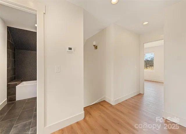 a view of hallway with bathroom and wooden floor