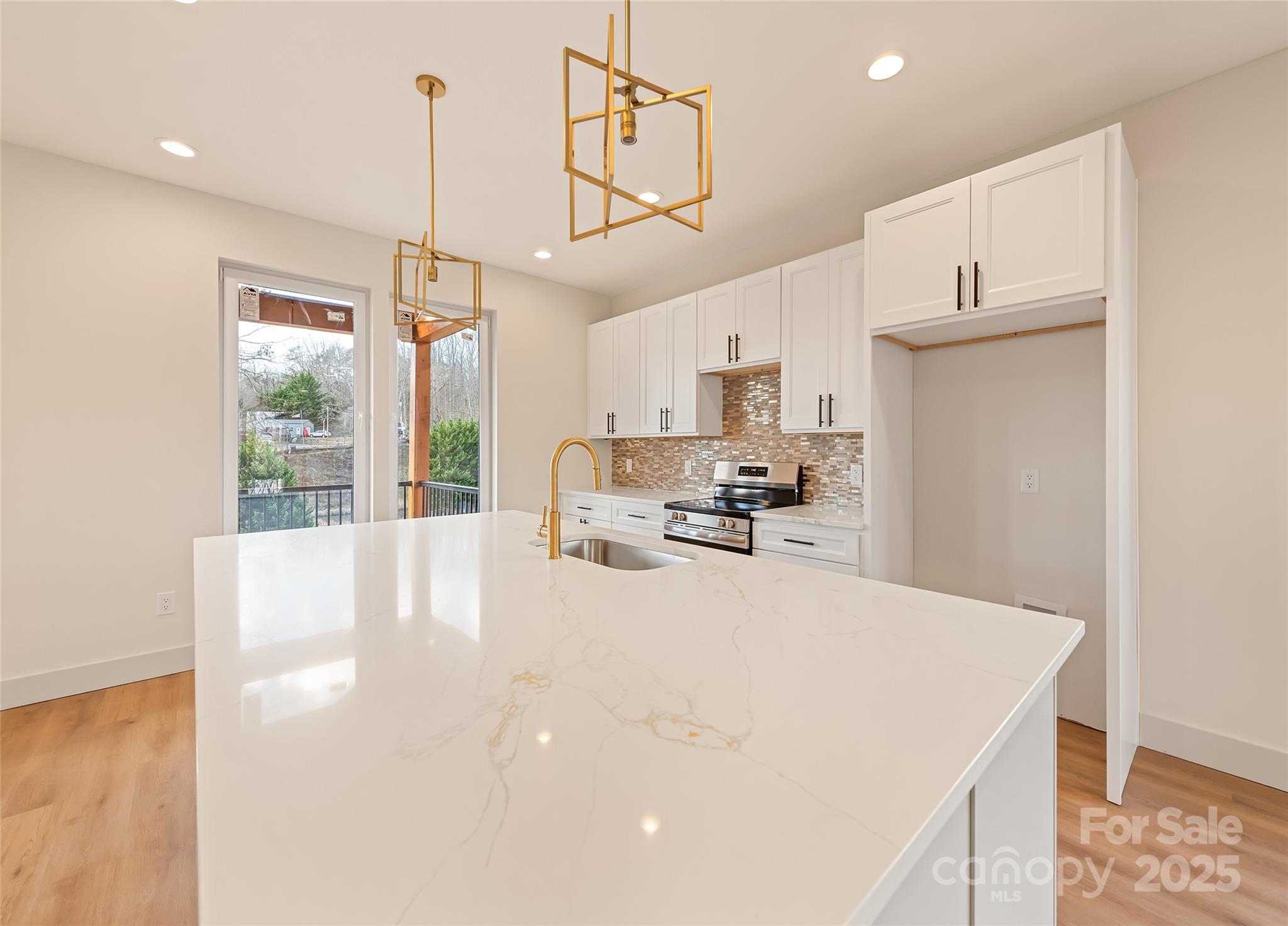 40 Firefly Ridge Trail Alexander, NC 28701 - Photo 9 of 33 a large white kitchen with kitchen island a stove a refrigerator a sink dishwasher and white cabinets with wooden floor