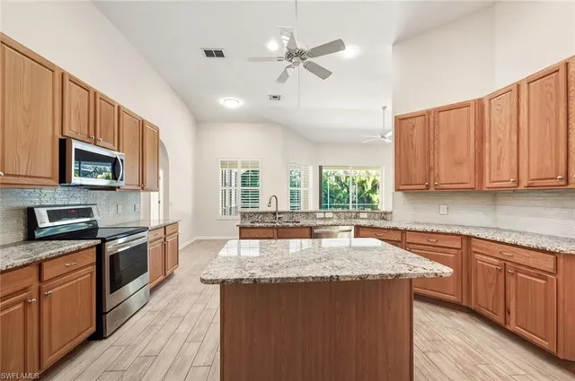 a kitchen with granite countertop wooden cabinets a sink dishwasher and a stove with wooden floor
