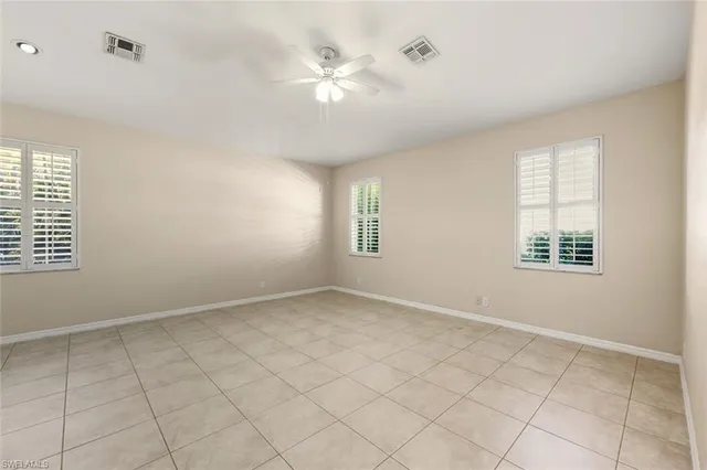 an empty room with windows and ceiling fan