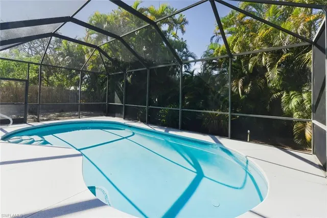 a view of a swimming pool with a yard and wooden fence