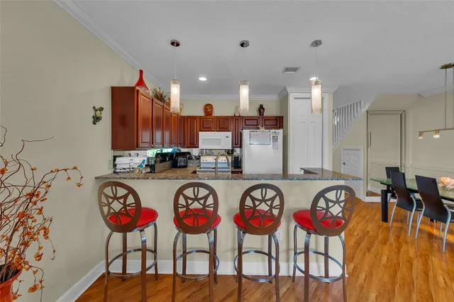 a group of chairs sitting in a kitchen with kitchen island stainless steel appliances refrigerator sink and wooden floor