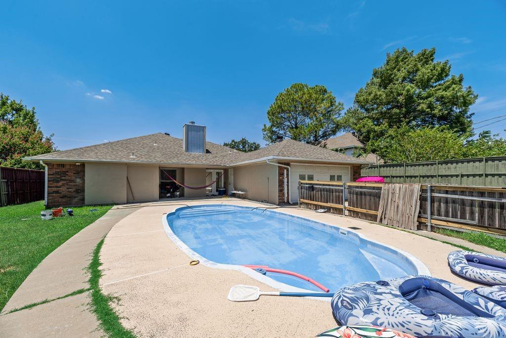 5114 Ben Davis Road Sachse, TX 75048 - Photo 16 of 28 Rear exterior featuring an in-ground swimming pool with a covered surface, an expansive pool deck, and a stucco and brick-veneer facade